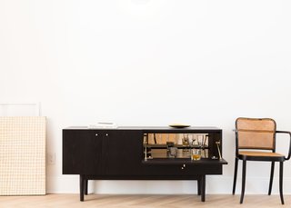 A drop-down door in Coil + Drift’s Rex credenza reveals a mirrored compartment ideal for barware display and storage.