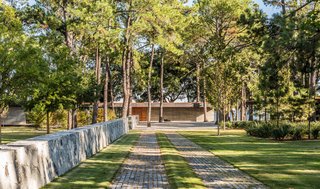 On the exterior of the low-lying, 4,690-square-foot home, the façade combines board-formed concrete, a teak front door, and weathered metal.