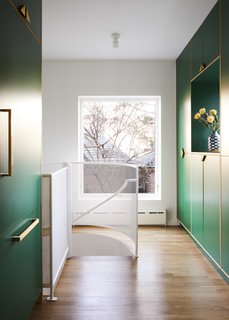 "White space was preserved in the kitchen by creating a pantry in the addition," say the architects. They continued the "language" of the cabinetry, which also conceals the refrigerator, and inserted a custom spiral staircase to connect the main floor to the garden level. An enlarged rear window that can be seen from the entry brightens up the space.