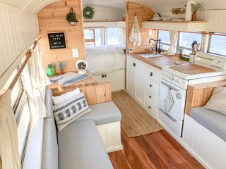 In order to keep the interior feeling light and airy, the couple combined white-painted vertical panelling with horizontal cedar planks on the walls. Acacia hardwood covers the floor. The kitchen counters are butcher block, and the curtain system is composed of copper tube rods and white linen. The mattress is a Full XL to maximize the available space, meaning it is the width of a full and the length of a queen.