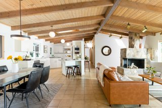 The simple white kitchen anchors the corner, with an eat-in bar for informal meals. Skylights bring lots of natural light into the room, as well as circulation areas like the hall and entryway.