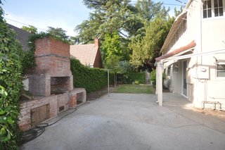 Before: "In the back, we added a deck off the back porch, transformed a crumbling brick fireplace into a wood-fired pizza oven, added a fire pit and fountain, as well as a kids’ play area with a swing set," says Valencia.