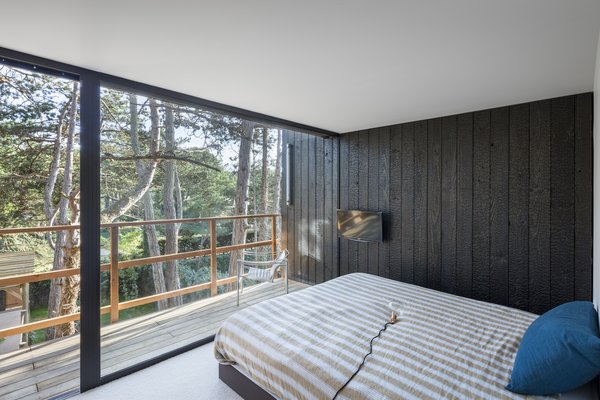 The charred wood siding carries into the home’s single bedroom, blurring the boundary between inside and out.