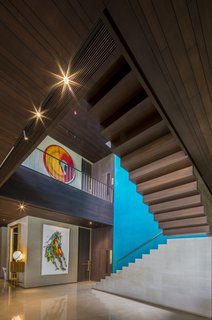 Wood stairs and walls warm up the double-height volume of the stairwell. Custom artwork can be found throughout the home.