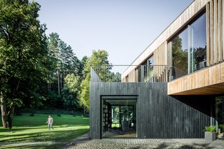 The vertical orientation of the exterior siding is meant to mimic the surrounding tree trunks in the natural setting. The wood siding was sourced from Kebony, "which modifies sustainably sourced softwoods by heating the wood with furfuryl alcohol—an agricultural byproduct," says the company. Doing so enables the softwoods to "permanently take on the attributes of tropical hardwood," relaying all the benefits of tropical hardwoods without relying on deforestation practices. The granite patio nods to traditional farmhouse foundations.