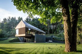 "The ground floor is partly hidden in the slope," say the architects, so as to make it seem as though it is receding into the landscape. The cantilevered volume houses the living room and creates protected space below for an outdoor patio.