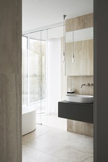 "A lot of the interiors included natural stone—completely unpolished and unsealed that we really wanted rough and exposed," says the firm. "Because the house is so minimal and clean, we wanted to create contrast within it. Unsealed travertine is so much more beautiful and natural than when it’s completely machined over."