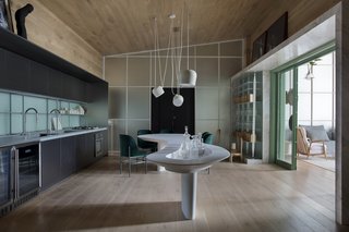 A marble "portal" breaks up the wood finishes and lowers the ceiling around the passageway between the living room and kitchen/dining area.