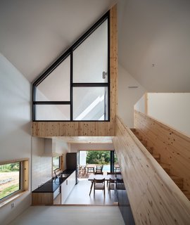 Wood cladding encases the ceiling of the kitchen at the lower level, covers the stairs, and defines the bedroom on the upper floor.