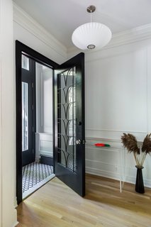 The vestibule is new, but attention to detail helps it blend in with the old. "Molding, casings, and wall paneling was replicated and reinstalled to create a new opening that looked like it had always been there," says Urban Pioneering Architecture. The glass door with the decorative metalwork is from Irreplaceable Artifacts, and the tile is the Circulos pattern from the Cement Tile Shop. 