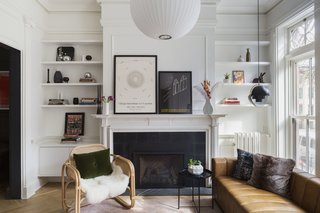 Custom shelving now flanks the fireplace, now composed of encaustic tile from the Cement Tile Shop and a marble hearth. A floating cabinet on one side balances an uncovered radiator on the other, and Benjamin Moore’s Chantilly Lace unifies the scheme. Throughout the first floor, Bona Traffic white oak floors with a matte finish is laid in a herringbone pattern.