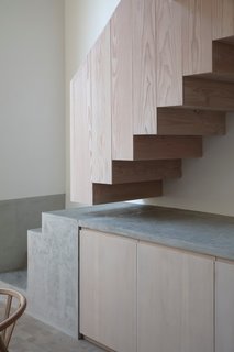 The staircase was moved to the other side of the room and is now a sculptural focal point, thanks to a striking material change from wood to concrete.