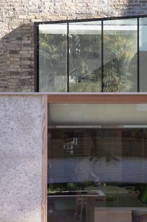 A detail shot shows how the rear extension was streamlined. “The extension at lower ground floor is finished with a natural Portland Roach stone with fossilized fragments,” said the firm. “The stone continues to form the surface of the patio, which is accessed from the kitchen via a bespoke Douglas fir-framed sliding door.”