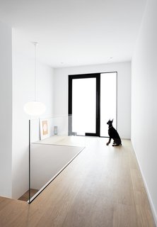 The white backdrop lets the black accents and wood grain in the pale, white-washed flooring stand out. A frameless glass railing melds with the surroundings.