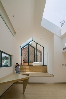 Occupants on the roof terrace can look down into the addition via the skylight. A narrow window over the table affords a view of the street, and the built-in table’s triangular shape saves space.