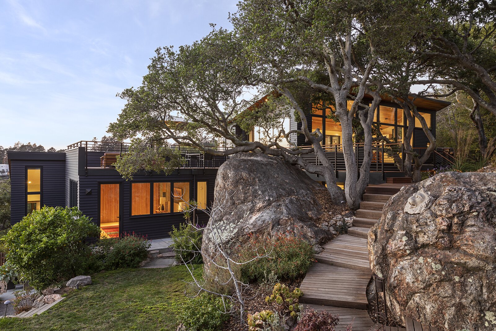 The original home was converted into a bedroom level, and given a second-story addition and roof deck. The dark exterior color, a charcoal-eggplant hue, lets the landscape colors stand out in contrast. 