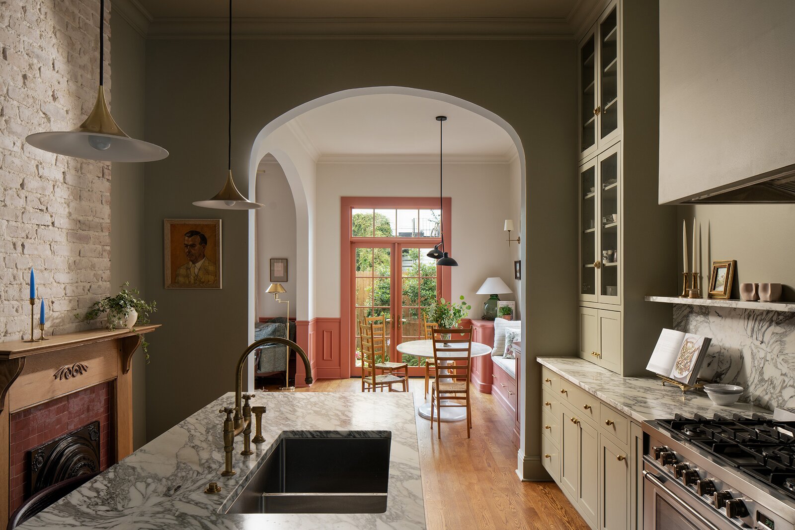 An arched opening was added to connect the kitchen and breakfast nook, and gain sightlines to the yard. Seamus refinished the fireplace mantle and added square zellige Zia tile in ‘Nana’s Lipstick’ to the surround. Gubi Semi Pendants hang over the island, and the sink has a Devol Ionian Bridge Tap.
