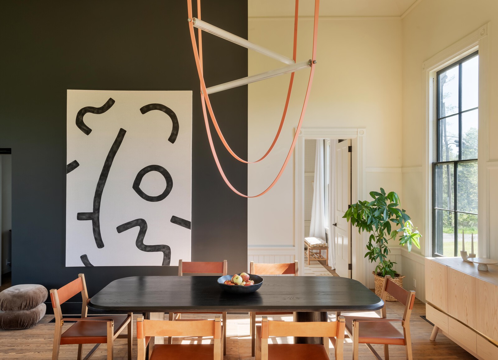 In the dining room, a Lulu and Georgia table is surrounded by Maria Yee chairs and overhead is a Flos light. The stairs act as buffer between the main rooms and bedrooms. The painting is by Mimia to fit the scale of the room.