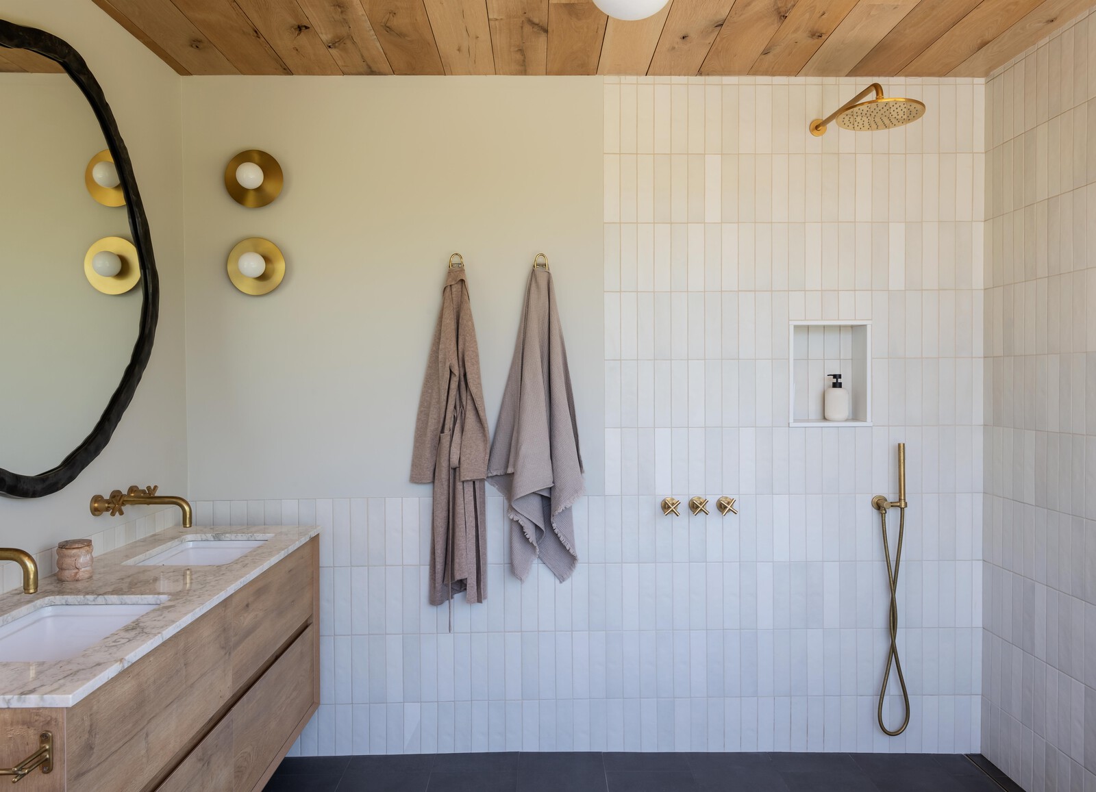Bedrosians tile covers the walls and floor, with sconces by Kelly Wearstler for Visual Comfort and California Faucets.