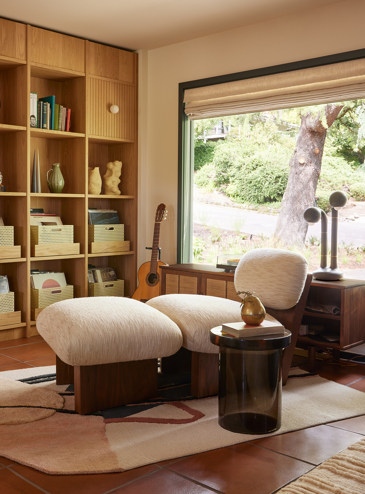 Across from the living room, the record-listening station has custom oak wall shelving fabricated by Maple Key with powder-coated perforated steel record baskets by local studio Boy Boy. An Atelier de Troupe chair sits atop a Faye TooGood Rug by CC Tapis.