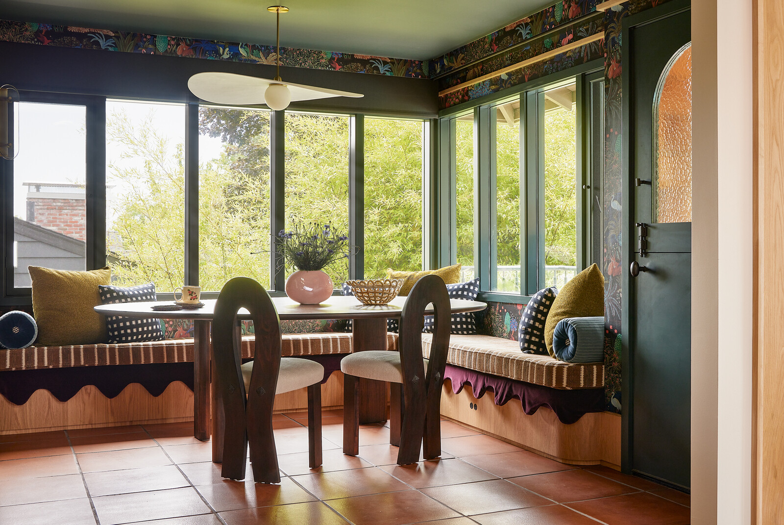 The dining area has a built-in bench with burgundy velvet scalloped upholstery, overhead light by Ladies &amp; Gentleman Studio, and a custom table from Campagna, a Portland-based furniture maker.