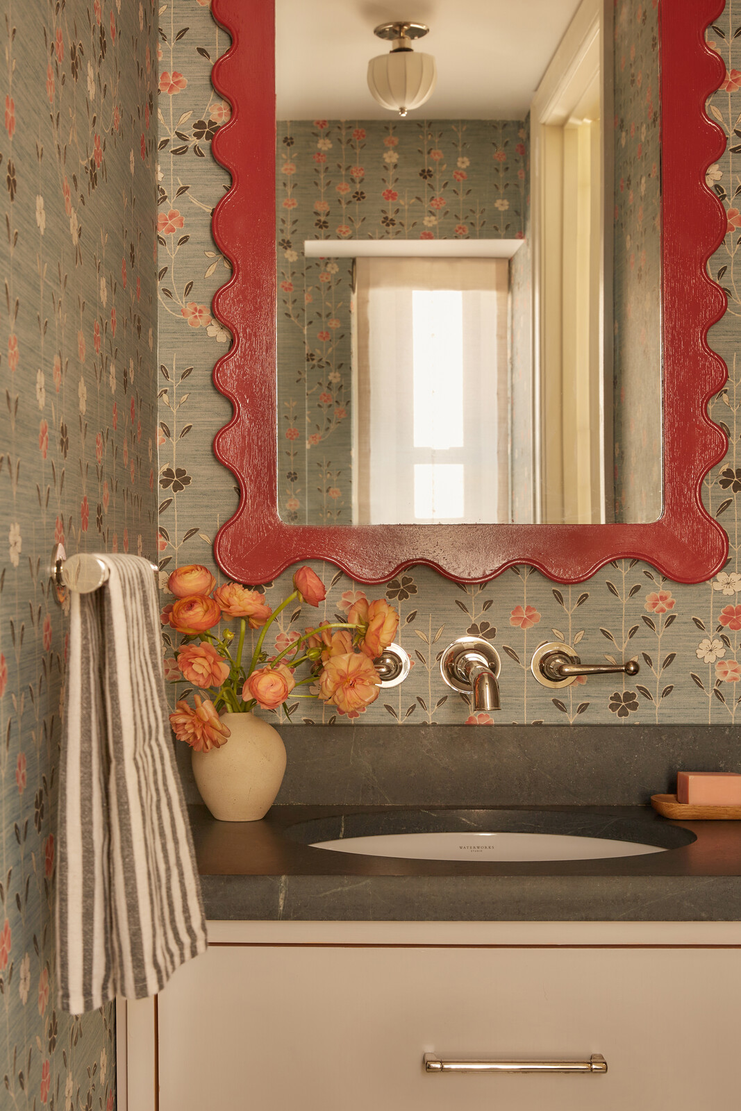 Lewis and Wood 'Blossom' wallpaper covers the walls, with a soapstone counter and Waterworks plumbing fittings.