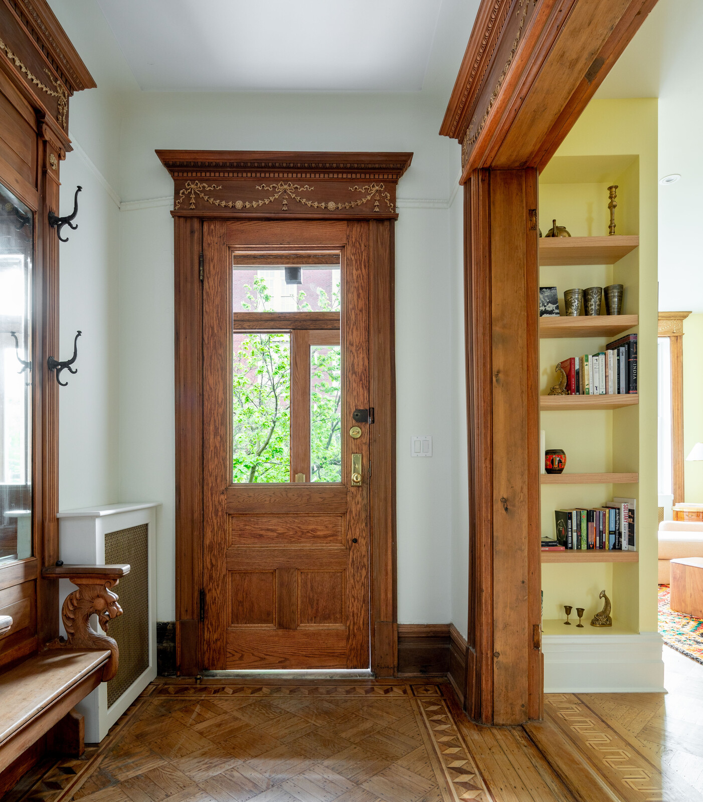 The shelving niche in the living room marks where a new coat closet went in, accessed in the entry vestibule.