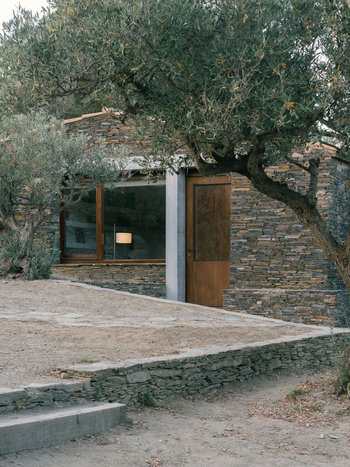 A concrete lintel and post marks the new window and door in the facade. The building's position makes inhabitants feel like they are hunkered down in the olive grove.