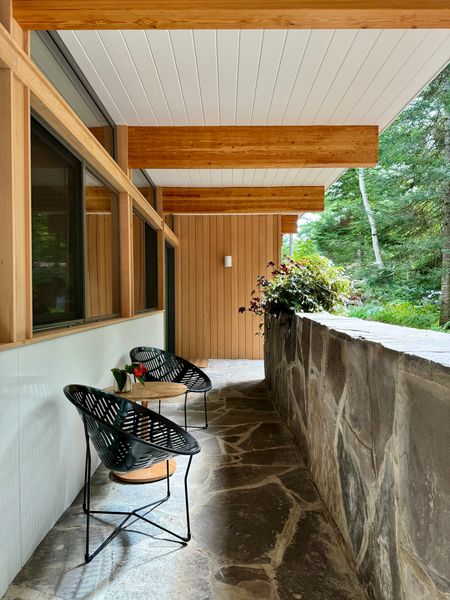 A covered porch with a flagstone floor and wall is a cool, shady spot out of the sun.