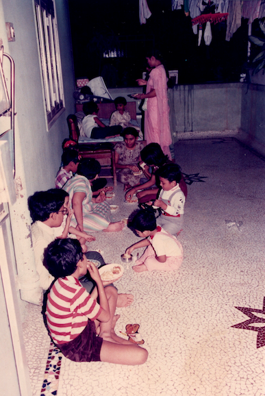 In 1990, Vineet and his brother and cousins enjoy a snack on the balcony.