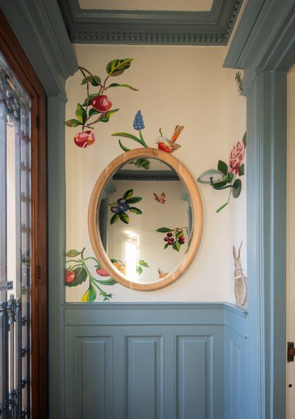 The designers commissioned multidisciplinary artist Evan Paul English for a custom mural featuring a floral and animal motif, where bunnies peak around corners and birds perch atop the mirror frame.