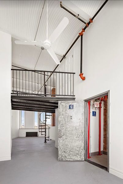 Before: The loft had a mezzanine level accessed by a small spiral staircase, and a lot of drywall covering the original brick walls.