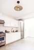 Modern home with Kitchen, White Cabinet, Range, Refrigerator, Ceiling Lighting, Dishwasher, Concrete Floor, Range Hood, Engineered Quartz Counter, and Undermount Sink. The functional one-wall kitchen is open to the first floor dining and living area. Photo 2 of 21st Street Cottage Remodel