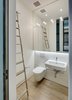 Modern home with Quartzite Counter, White Cabinet, Medium Hardwood Floor, Mirror Backsplashe, Refrigerator, Cooktops, Wall Oven, Range Hood, Microwave, Dishwasher, Wine Cooler, Interior, Metal, Sliding Door Type, Bath Room, Wall Mount Sink, Accent Lighting, Ceiling Lighting, Wall Lighting, and Stone Slab Wall. Upper Level: Powder Room (stores rolling ladder for access to the Kitchen and Master Bedroom upper cabinets). Photo 6 of Noho Duplex, New York