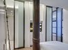 Modern home with Refrigerator, Quartzite Counter, Medium Hardwood Floor, White Cabinet, Mirror Backsplashe, Cooktops, Wall Oven, Range Hood, Microwave, Dishwasher, Wine Cooler, Interior, Metal, Sliding Door Type, Ceiling Lighting, Accent Lighting, Stone Slab Wall, Bed, Undermount Sink, and Storage Room. Upper Level: Compact Master Bedroom and Master Bathroom Suite. Photo 7 of Noho Duplex, New York