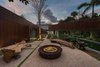 Modern home with Gardens, Trees, Sofa, Limestone Floor, Shrubs, Concrete Patio, Porch, Deck, Chair, Stone Counter, Wood Cabinet, Range Hood, Range, Drop In Sink, Table, Bed, Recessed Lighting, Bench, Night Stands, Freestanding Tub, Open Shower, and Full Shower. A secluded seating area features natural teak wood benches and a fire pit. Photo 12 of Pine Tree North