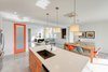 Modern home with Dresser, Undermount Sink, Bed, Engineered Quartz Counter, Chair, Carpet Floor, Alcove Tub, Ceiling Lighting, Ceramic Tile Wall, Two Piece Toilet, Trees, Shrubs, Grass, Walkways, Back Yard, Large Patio, Porch, Deck, Sofa, Concrete Floor, Table, and Stools. kitchen, dining, and living Photo 9 of Cedarbrook Net Zero Modern