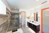 Modern home with Dresser, Undermount Sink, Bed, Chair, Carpet Floor, Alcove Tub, Ceiling Lighting, Ceramic Tile Wall, Two Piece Toilet, Engineered Quartz Counter, Trees, Shrubs, Grass, Walkways, Back Yard, Large Patio, Porch, Deck, Sofa, Concrete Floor, Table, and Stools. master bath Photo 13 of Cedarbrook Net Zero Modern