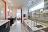 Modern home with Bed, Undermount Sink, Engineered Quartz Counter, Dresser, Chair, Carpet Floor, Ceiling Lighting, Ceramic Tile Wall, Two Piece Toilet, Trees, Shrubs, Grass, Walkways, Back Yard, Large Patio, Porch, Deck, Sofa, Concrete Floor, Table, Stools, and Pendant Lighting. master bath Photo 14 of Cedarbrook Net Zero Modern