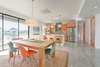 Modern home with Dresser, Undermount Sink, Bed, Engineered Quartz Counter, Chair, Carpet Floor, Alcove Tub, Ceiling Lighting, Ceramic Tile Wall, Two Piece Toilet, Trees, Shrubs, Grass, Walkways, Back Yard, Large Patio, Porch, Deck, Sofa, Concrete Floor, Bench, and Kitchen. dining and kitchen Photo 8 of Cedarbrook Net Zero Modern