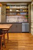 Modern home with Kitchen, Undermount Sink, Medium Hardwood Floor, Ceiling Lighting, Ceramic Tile Backsplashe, Wood Counter, Dishwasher, Colorful Cabinet, and Accent Lighting. A custom rolling door system screens everyday kitchen items. Photo 5 of Dolores Street