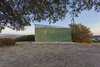 Modern home with Wood Cabinet, Coffee Tables, Wood Counter, Metal Cabinet, Concrete Floor, Chair, Table, Trees, Shrubs, Small Patio, Porch, Deck, Exterior, Metal, Folding Door Type, Metal Counter, Living Space Room Type, Bed, Accent Lighting, and Outdoor. View from the olive tree Photo 13 of The Olive Tree House