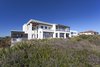 Modern home with Bed, Ceiling Lighting, Engineered Quartz Counter, Undermount Sink, Freestanding Tub, Enclosed Shower, Front Yard, Trees, Shrubs, Grass, Walkways, White Cabinet, Wood Cabinet, Landscape Lighting, Outdoor, and Travertine Floor. Looking back at the house over the dune form the beach Photo 8 of NJPV