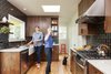 Modern home with Kitchen, Quartzite Counter, Wood Cabinet, Medium Hardwood Floor, Ceramic Tile Backsplashe, Ceiling Lighting, Range, and Drop In Sink. Tall, dark, and handsome: We aimed for midcentury-inspired design, while respecting the long lines and existing layout of this 1909 home. Photo 6 of Holly + Magda