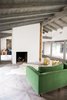 Modern home with Living Room, End Tables, Sofa, Track Lighting, Ottomans, Porcelain Tile Floor, and Two-Sided Fireplace. The original fireplace was a rugged rock monolith that extended all the way to the exterior wall and several feet closer to the front windows. The stone facade was stripped away, which opened up a walkway to the den. The two-sided fireplace column was wrapped with crisp white drywall. Photo 9 of Diablo Ranch