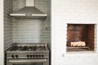 The kitchen fireplace is one of three original to the house, and its traditional staggered brick design became the inspiration for the stagger-set undulating gray porcelain subway tile backsplash.