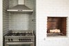 Modern home with Kitchen, Subway Tile Backsplashe, Porcelain Tile Backsplashe, and Range. The kitchen fireplace is one of three original to the house, and its traditional staggered brick design became the inspiration for the stagger-set undulating gray porcelain subway tile backsplash. Photo 13 of Diablo Ranch