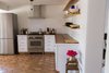 Modern home with Kitchen, Tile Counter, White Cabinet, Pendant Lighting, Ceramic Tile Floor, Range, and Ceramic Tile Backsplashe. Bertazzoni stove, ranch shelves, mid-century side table, Daltile Florentine Carrara porcelain backsplash Photo 7 of PILGRIM HOUSE