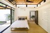 Modern home with Bedroom, Night Stands, Bed, Wall Lighting, and Rug Floor. Similar to the open spaces, the sleeping quarters have operable, sliding glass doors and clerestory windows allow the tropical air to freely pass between the exterior and interior. Photo 7 of Nalu Nosara