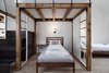 Modern home with Bedroom, Bed, Wall Lighting, Light Hardwood Floor, and Night Stands. Uniquely designed wood framing and bent metal stairs create a uniquely formed mezzanine and sleeping area with modern detailing. Photo 18 of Long Story Short Hostel